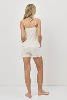 Woman wearing a beige tank top and shorts set on a white background