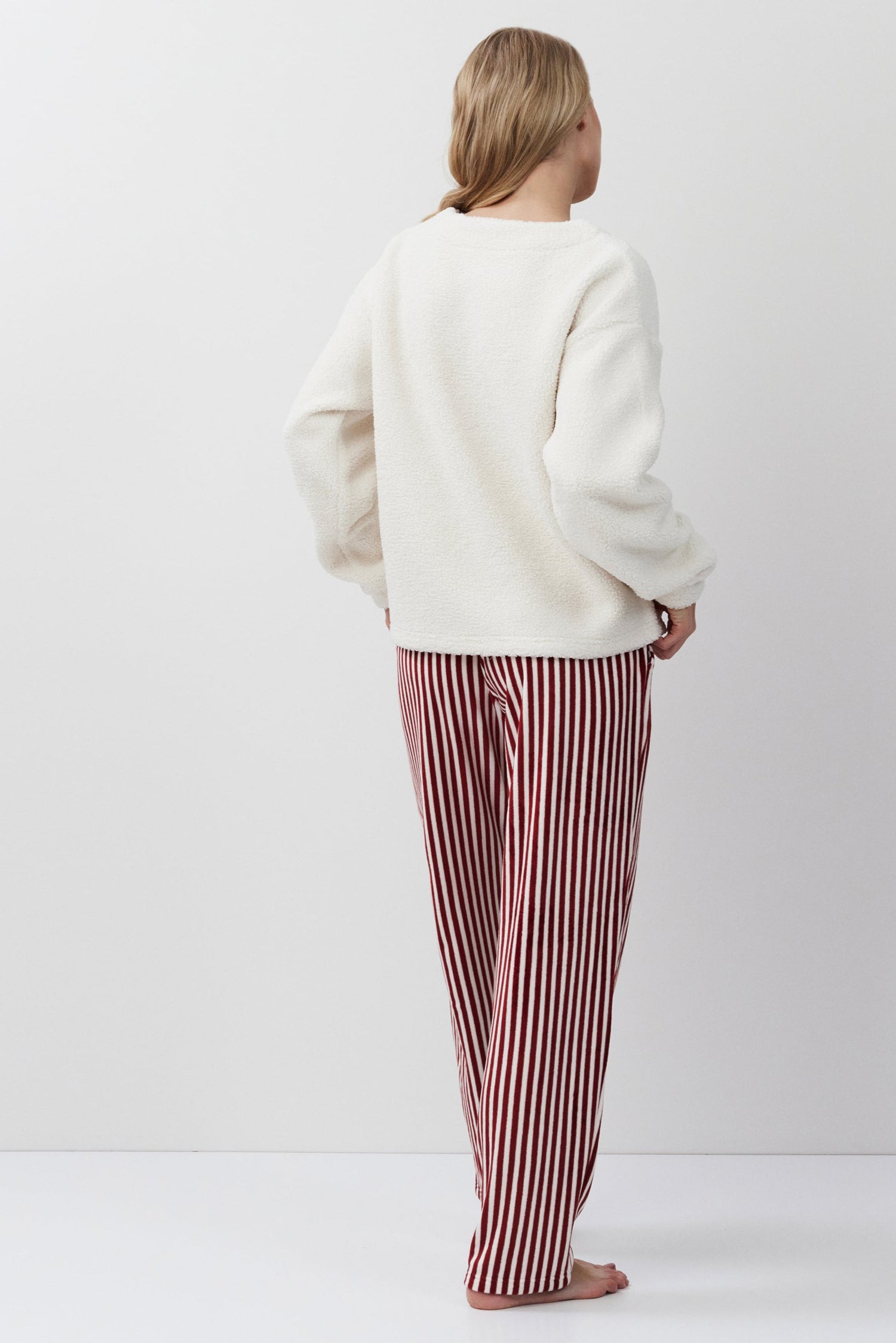 Person wearing a white sweater and red striped pants on a white background