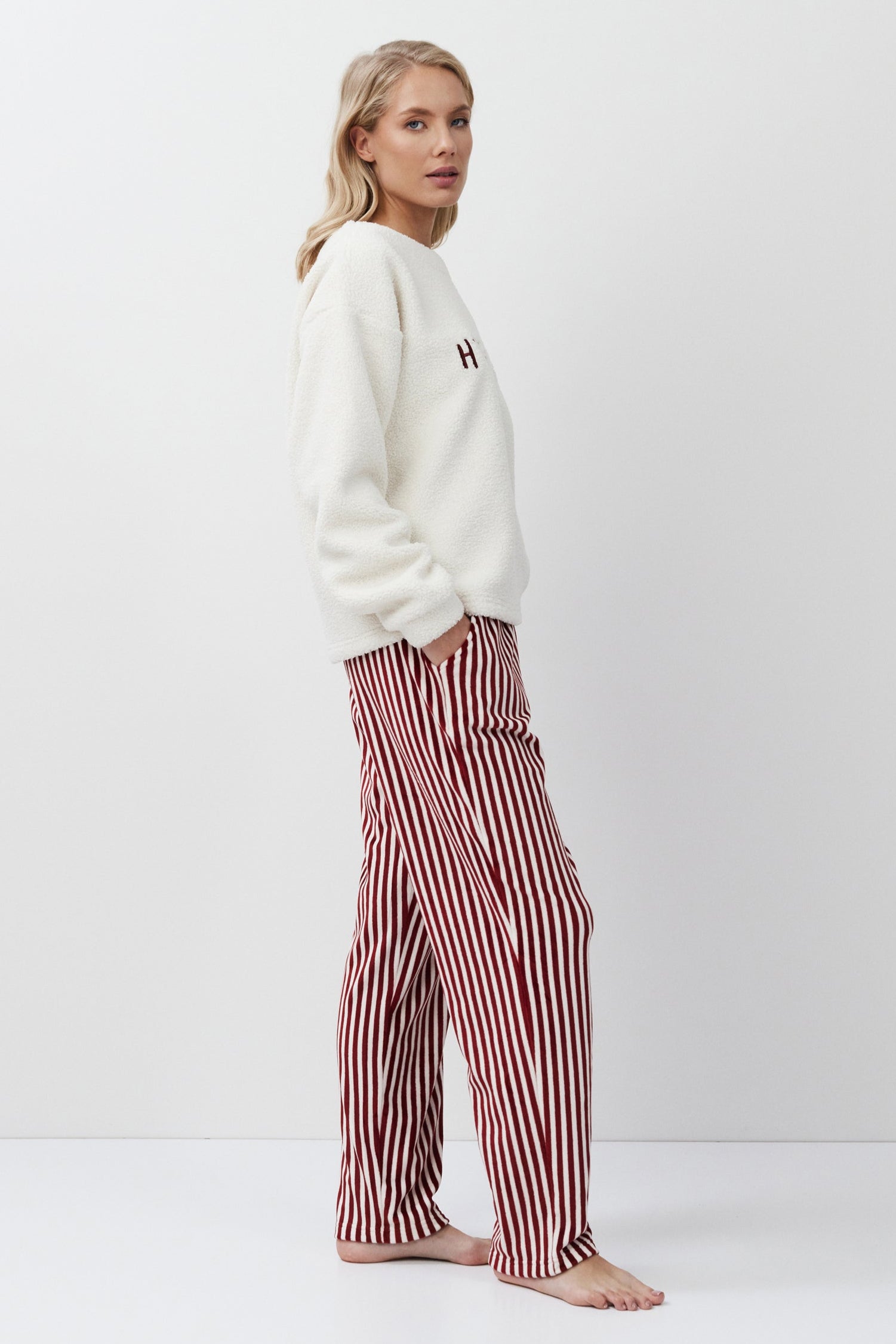 Woman wearing a white sweater and red striped pants on a white background