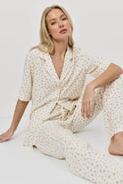 Woman wearing a cream-colored pajama set with a subtle pattern on a white background