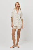 Woman wearing a butter yellow pajama set on a plain background