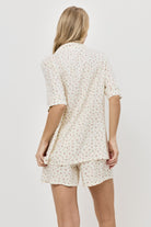 Woman wearing a butter yellow pajama set on a plain background