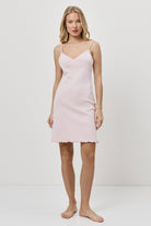 Woman wearing a light pink nightdress against a white background