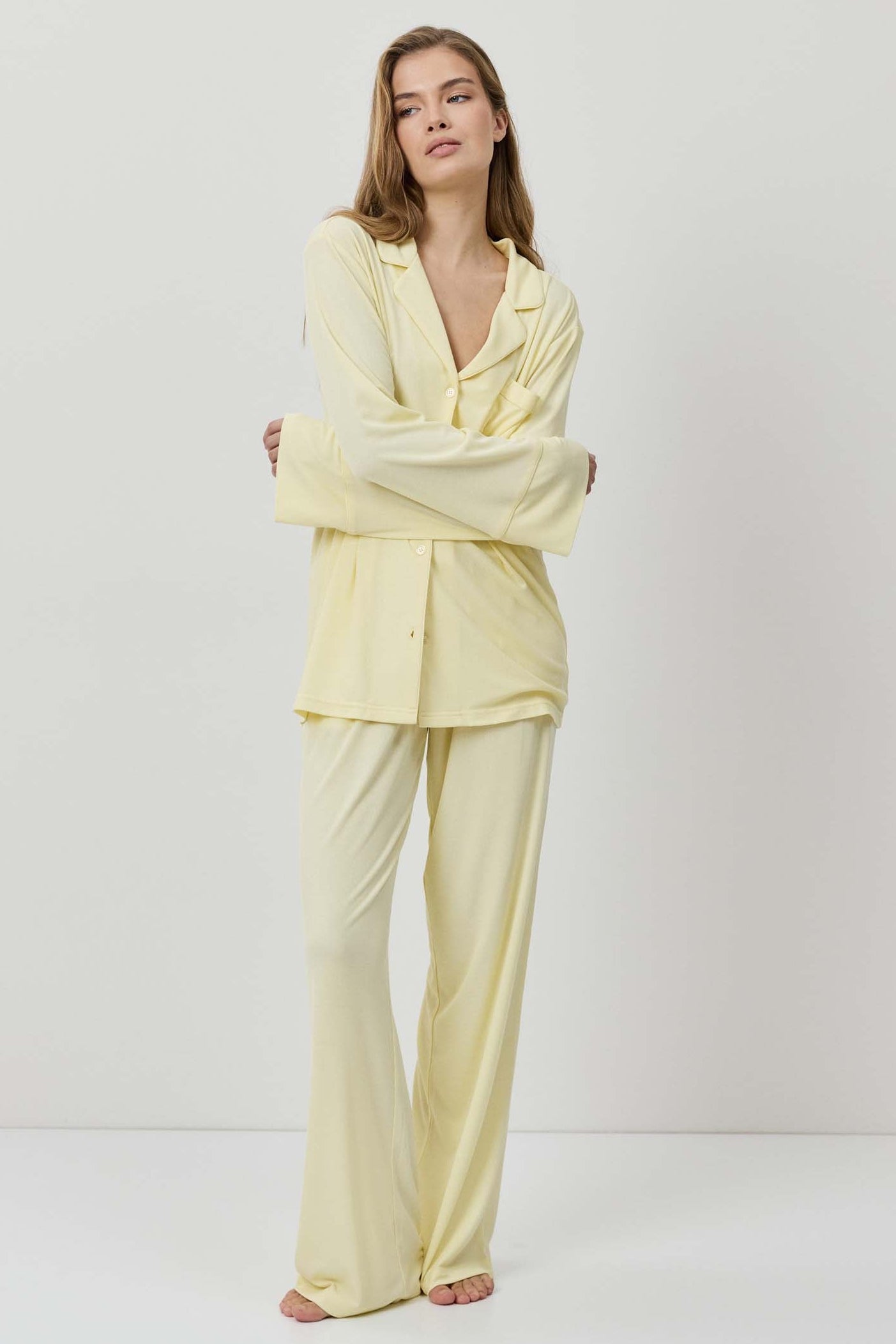 Woman wearing a light yellow pajama set against a white background