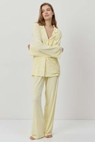 Woman wearing a light yellow pajama set against a white background