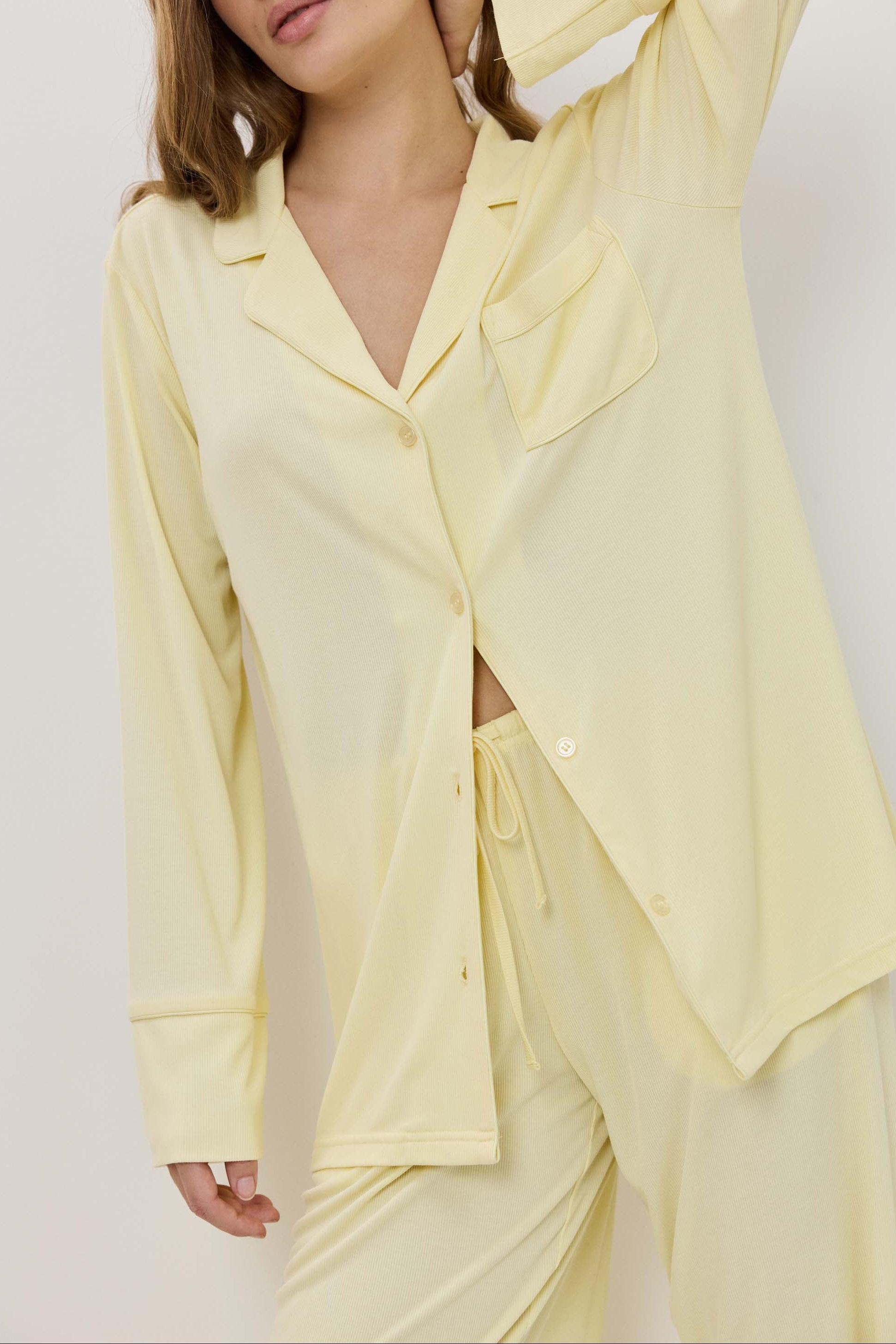 Woman wearing a light yellow pajama set against a white background