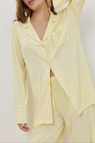 Woman wearing a light yellow pajama set against a white background