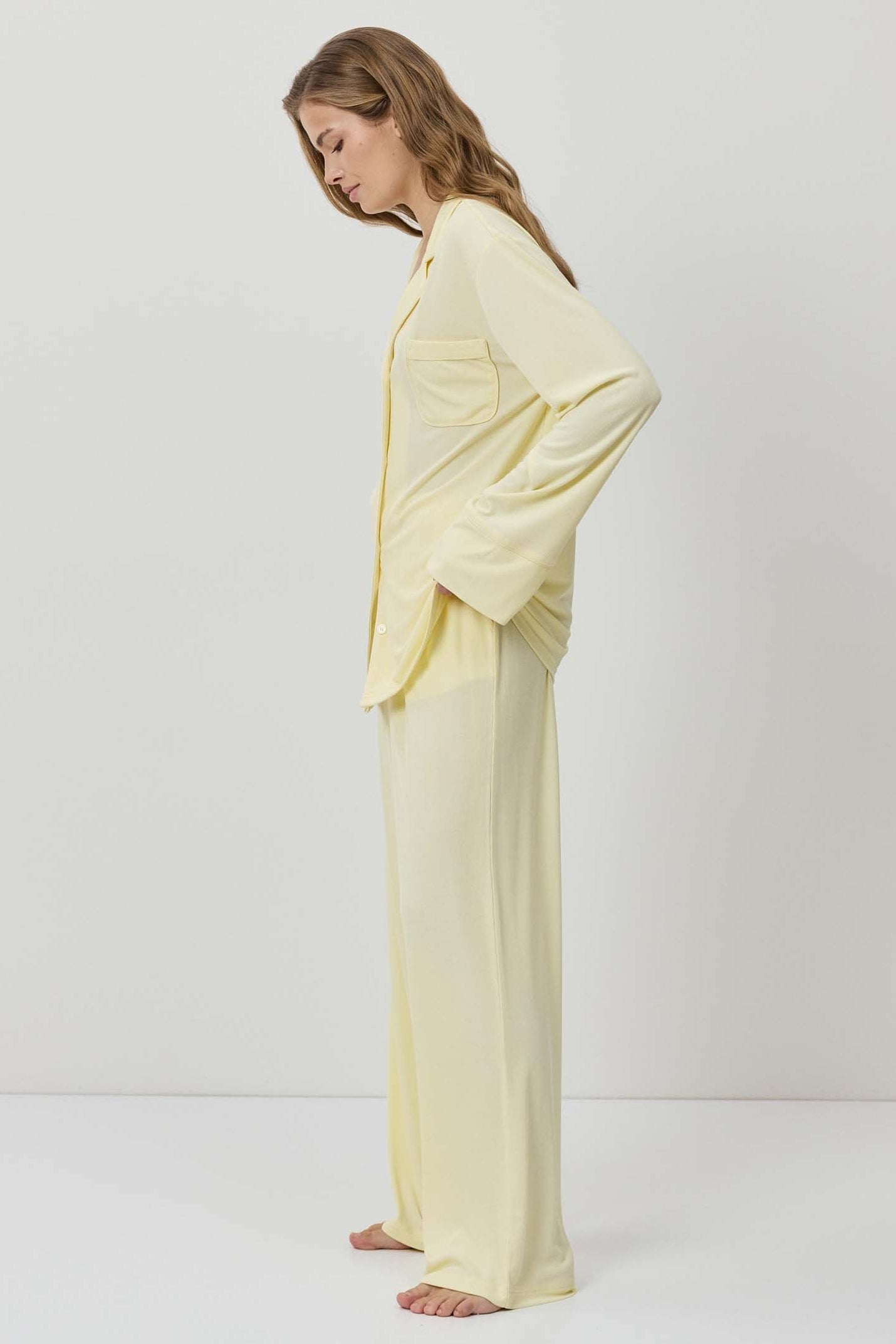 Woman wearing a light yellow pajama set against a white background