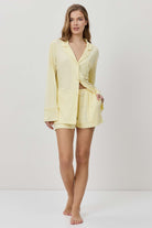 Woman wearing a light yellow robe and shorts on a white background