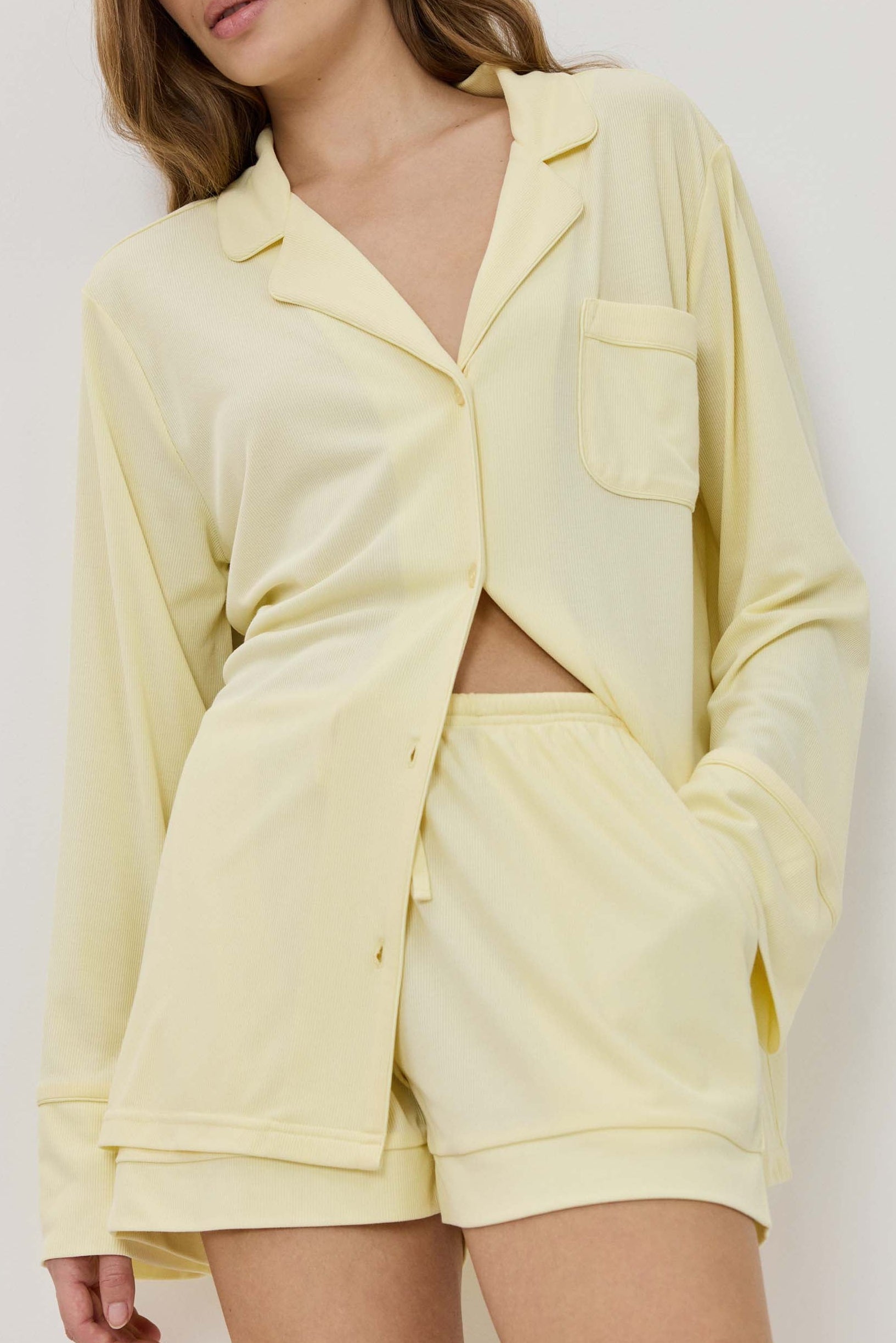 Woman wearing a light yellow lounge set against a white background