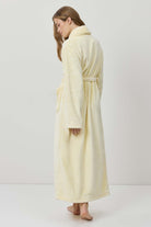 Woman wearing a long cream-colored robe against a white background