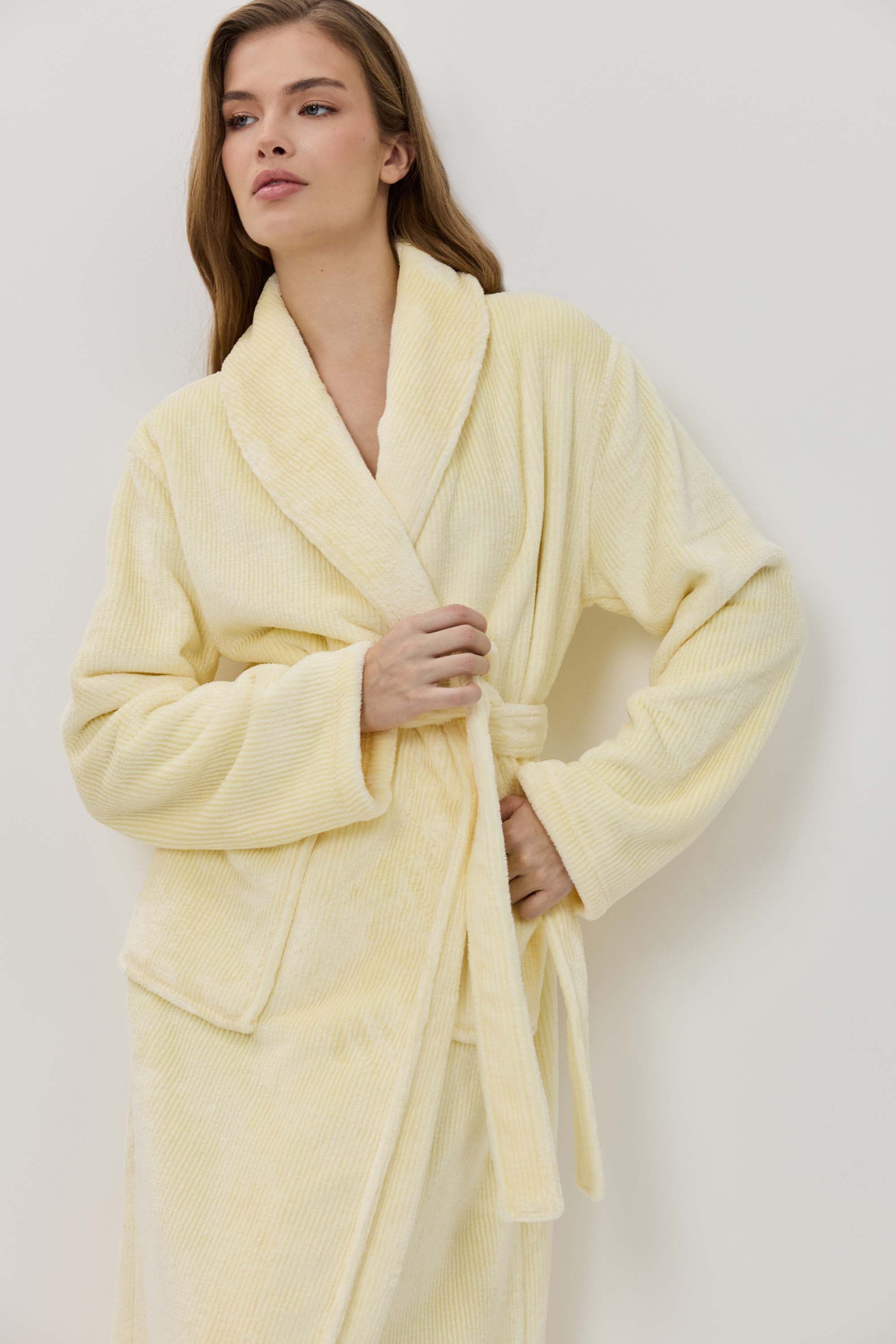 Woman wearing a light yellow robe against a white background