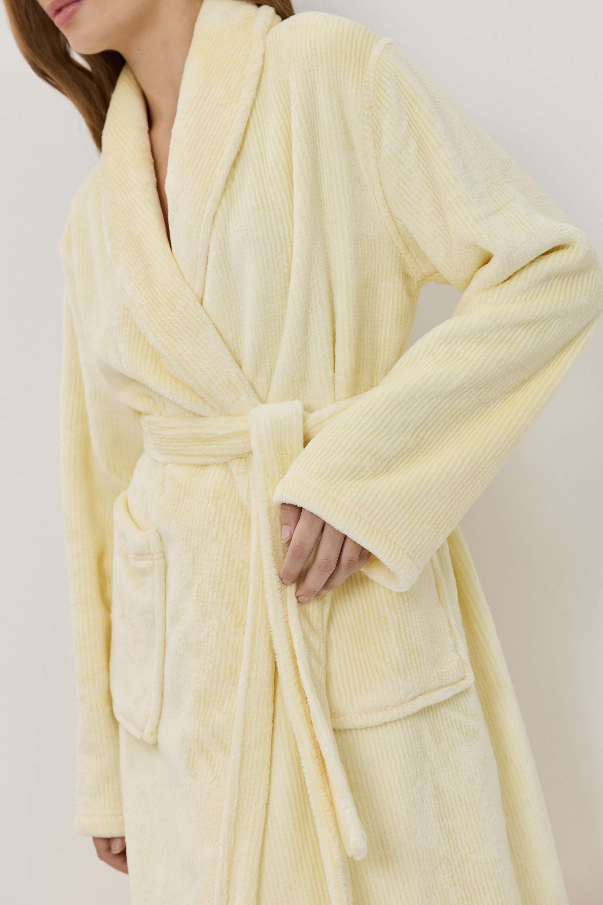 Person wearing a yellow robe against a plain background
