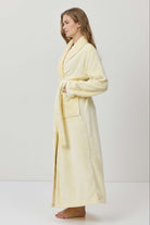 Woman wearing a light yellow bathrobe against a white background