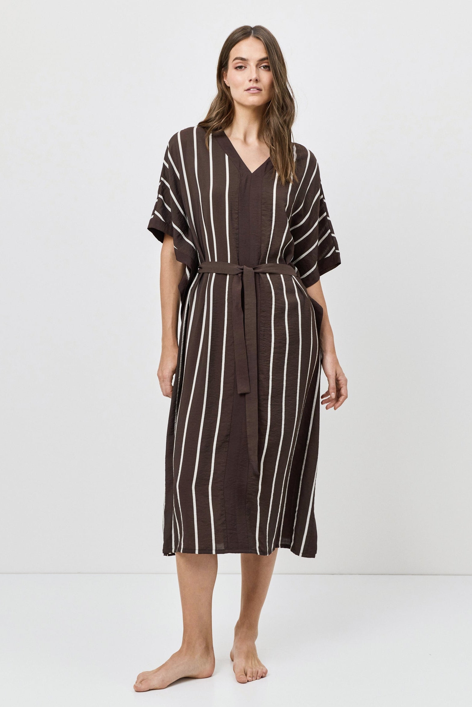 Woman wearing a brown and white striped dress on a white background