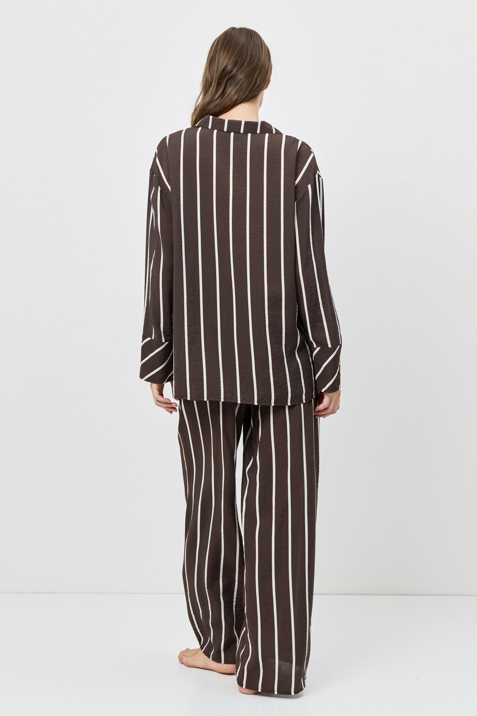 Person wearing a brown and white striped pajama set on a white background