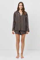 Woman wearing a brown and white striped shirt and shorts on a white background