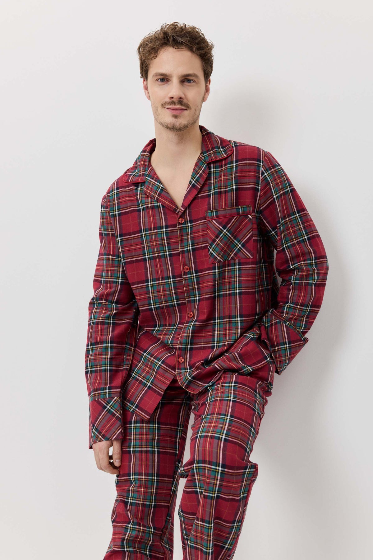 Man wearing red plaid pajamas against a white background