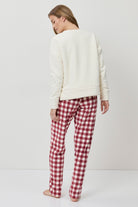 Person wearing a white sweater and red plaid pants on a white background