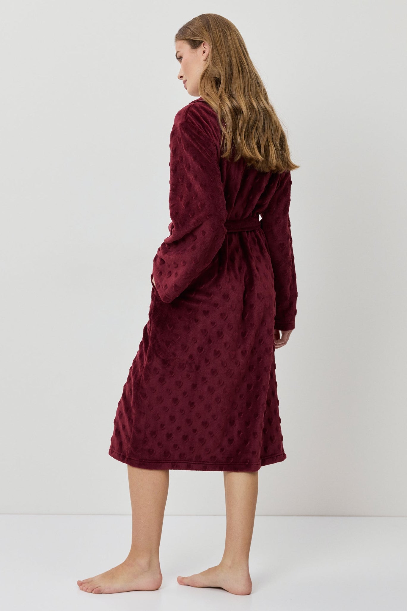 Woman wearing a burgundy textured dress against a white background