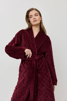 Woman wearing a burgundy robe against a white background