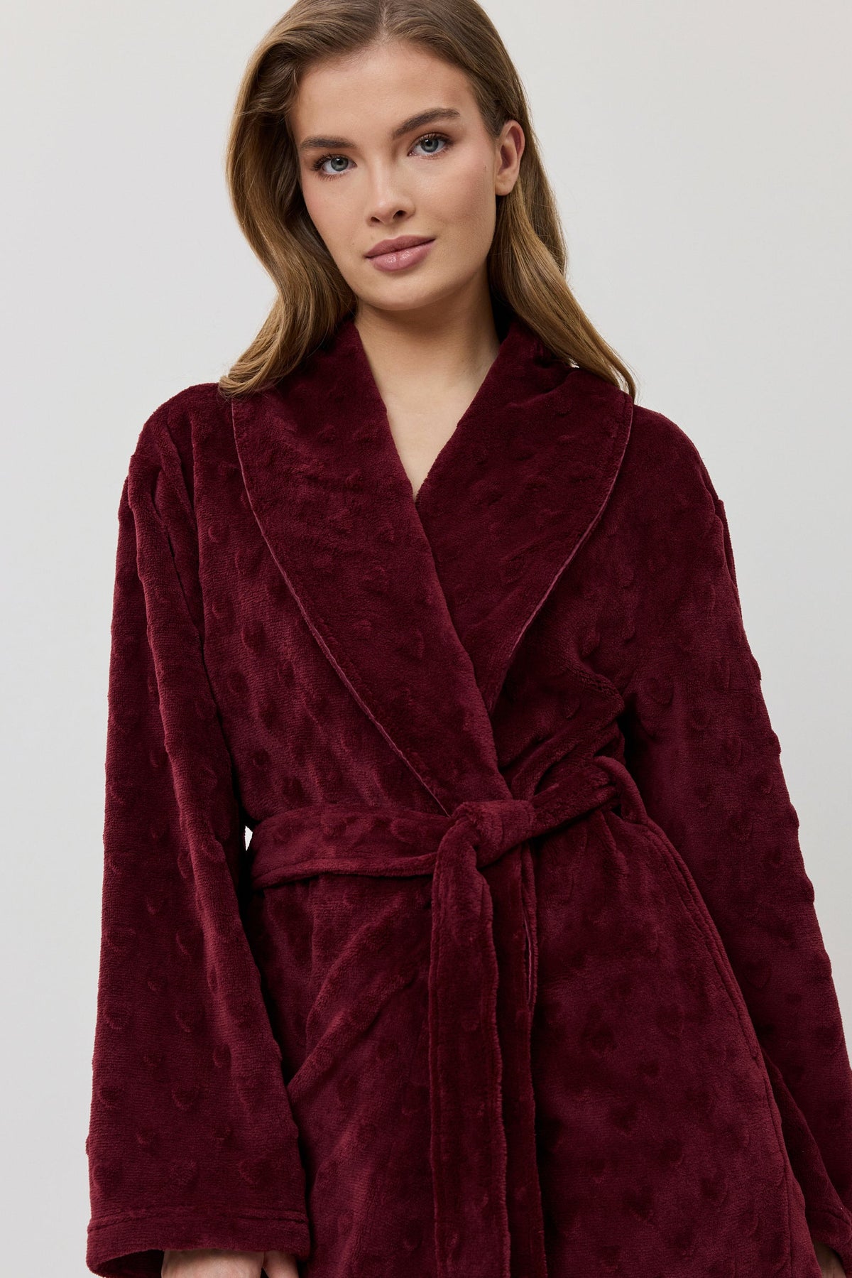 Woman wearing a burgundy robe against a white background