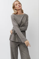 Woman wearing a brown long-sleeve top and pants on a white background