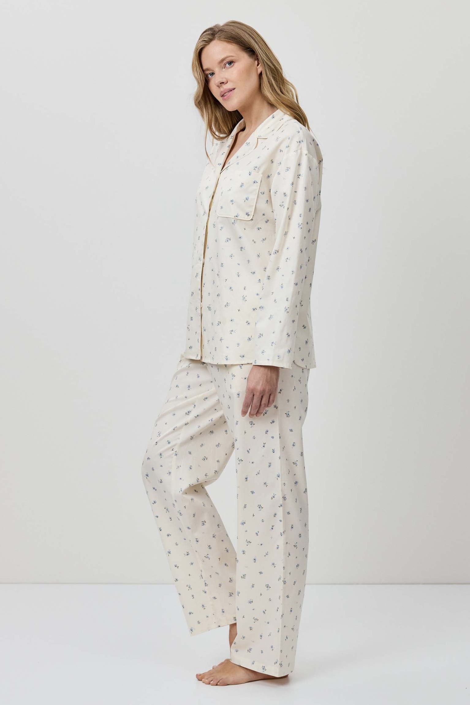 Woman wearing a white pajama set with a subtle pattern on a white background