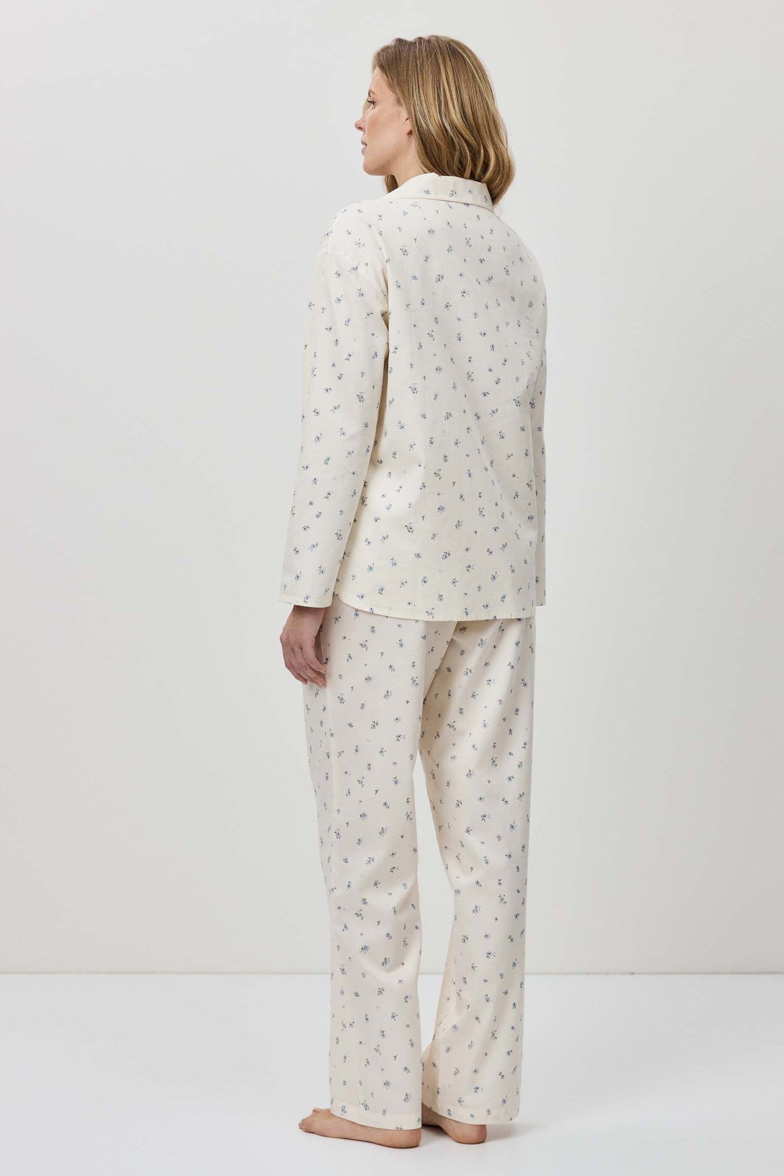 Person wearing a white pajama set with a subtle pattern on a plain background