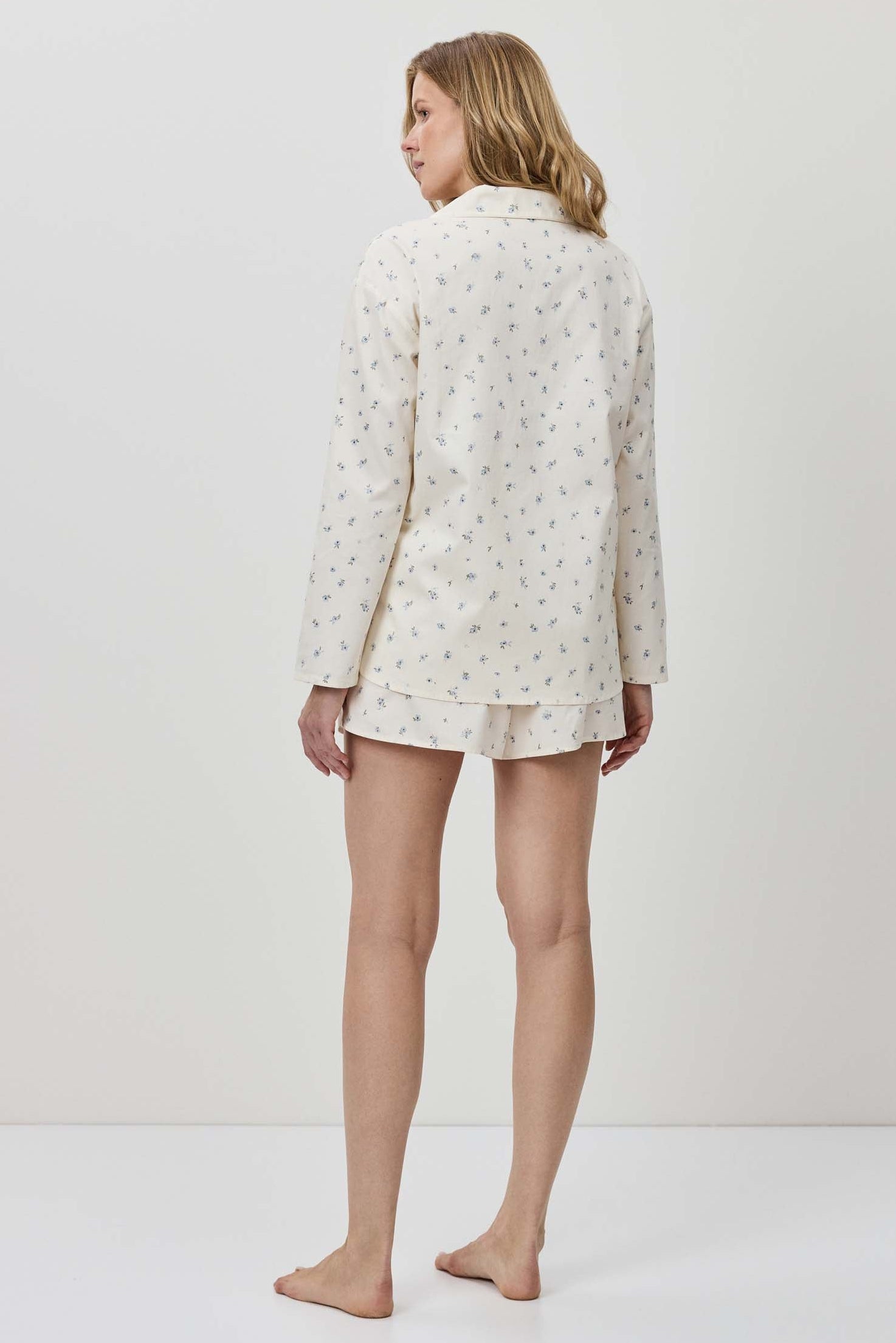 Person wearing a white floral pajama set on a plain background