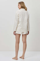 Person wearing a white floral pajama set on a plain background