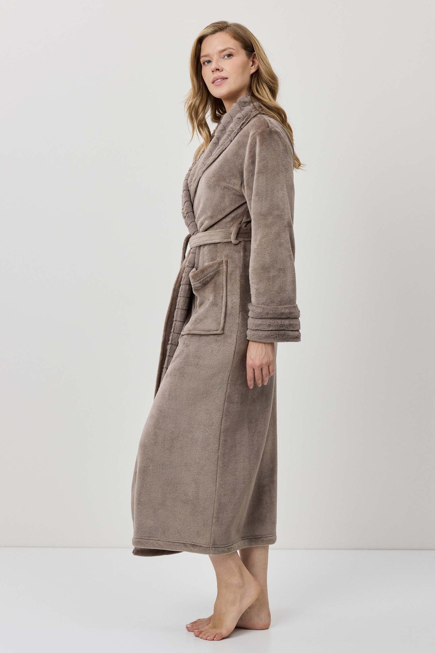 Woman wearing a long brown bathrobe on a white background