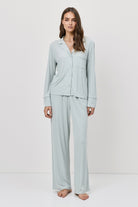 Woman wearing light blue pajama set against a white background