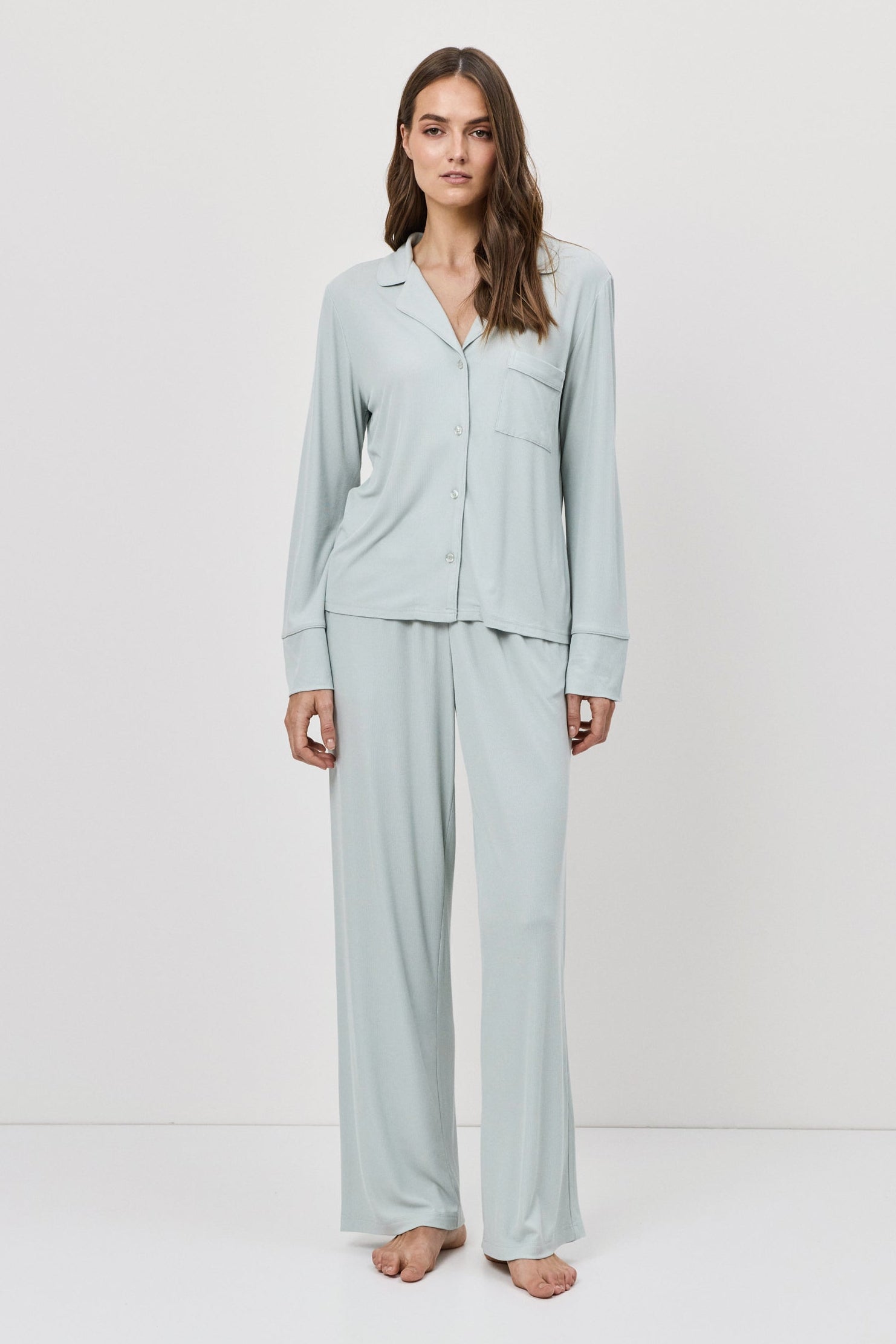 Woman wearing light blue pajama set against a white background