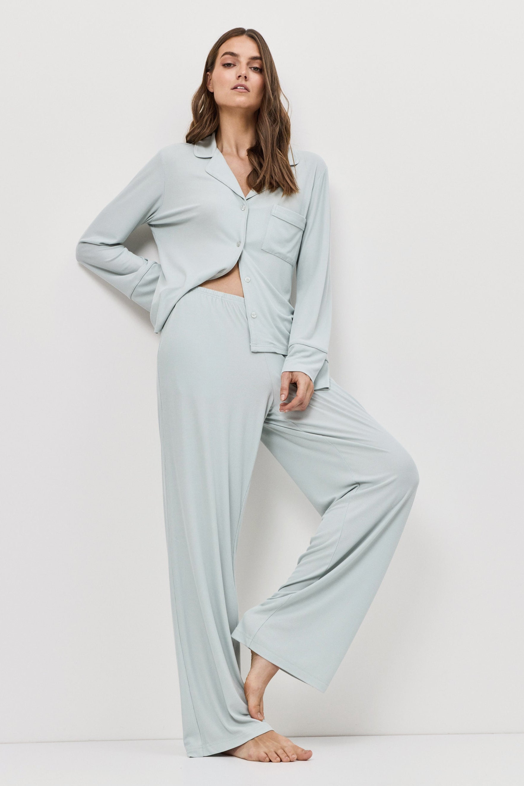 Woman wearing a light blue pajama set on a white background
