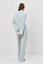 Woman wearing a light blue outfit standing against a white background