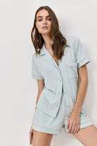 Woman wearing a light blue pajama set against a plain background