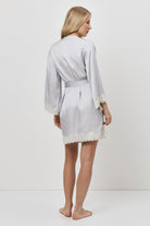 Woman wearing a light gray robe with lace trim on a white background