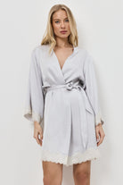 Woman wearing a light gray robe with lace trim on a white background