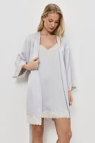 Woman wearing a light gray gown over a gray nightdress on a plain background