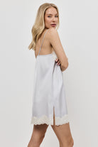 Woman wearing a gray  nightdress with lace trim on a plain background