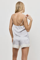 Woman wearing a gray pajama set lace trim on a plain background