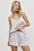 Woman wearing a gray lace top and shorts set on a plain background