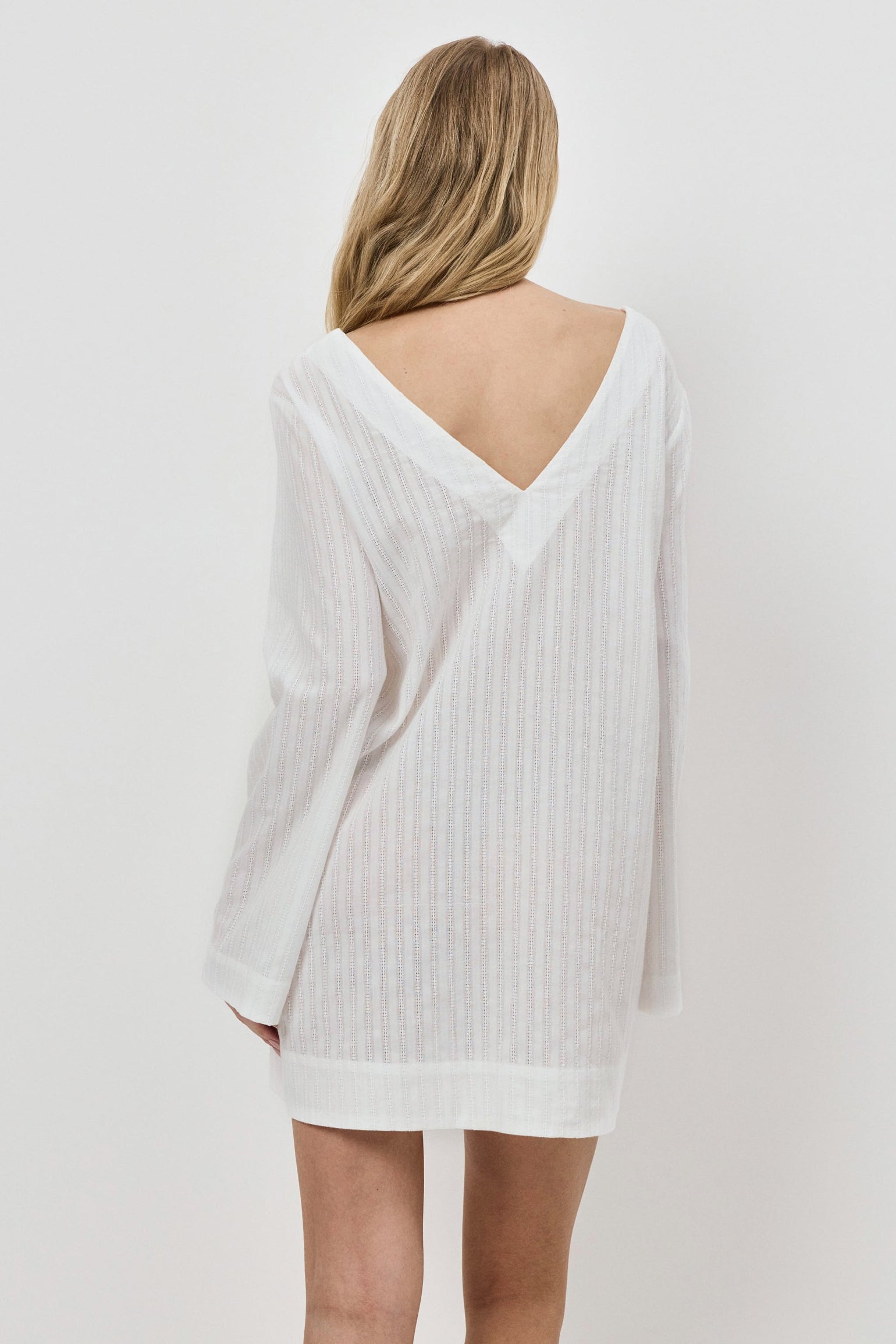 Person wearing a white dress against a plain background