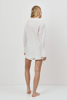 Person wearing a white long-sleeve resort weatr shirt and shorts on a white background