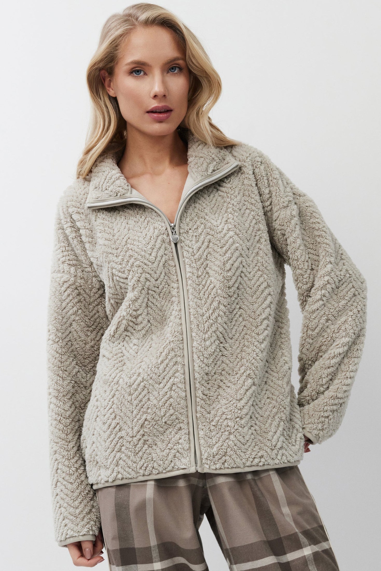 Woman wearing a sweater and plaid pants on a white background