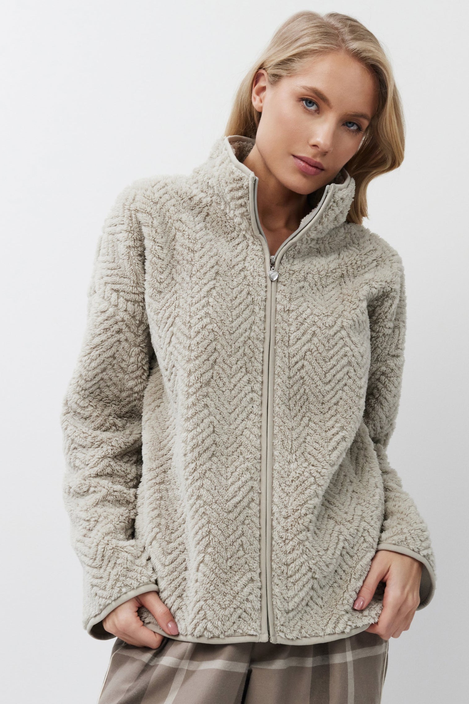 Woman wearing a sweater and plaid pants on a white background