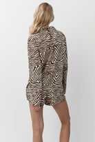 Person wearing a zebra print pajama set with shorts on a plain background