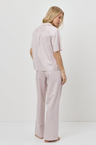 Woman wearing a pink striped pajama set on a white background
