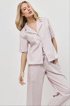 Woman wearing a pink striped outfit on a plain background